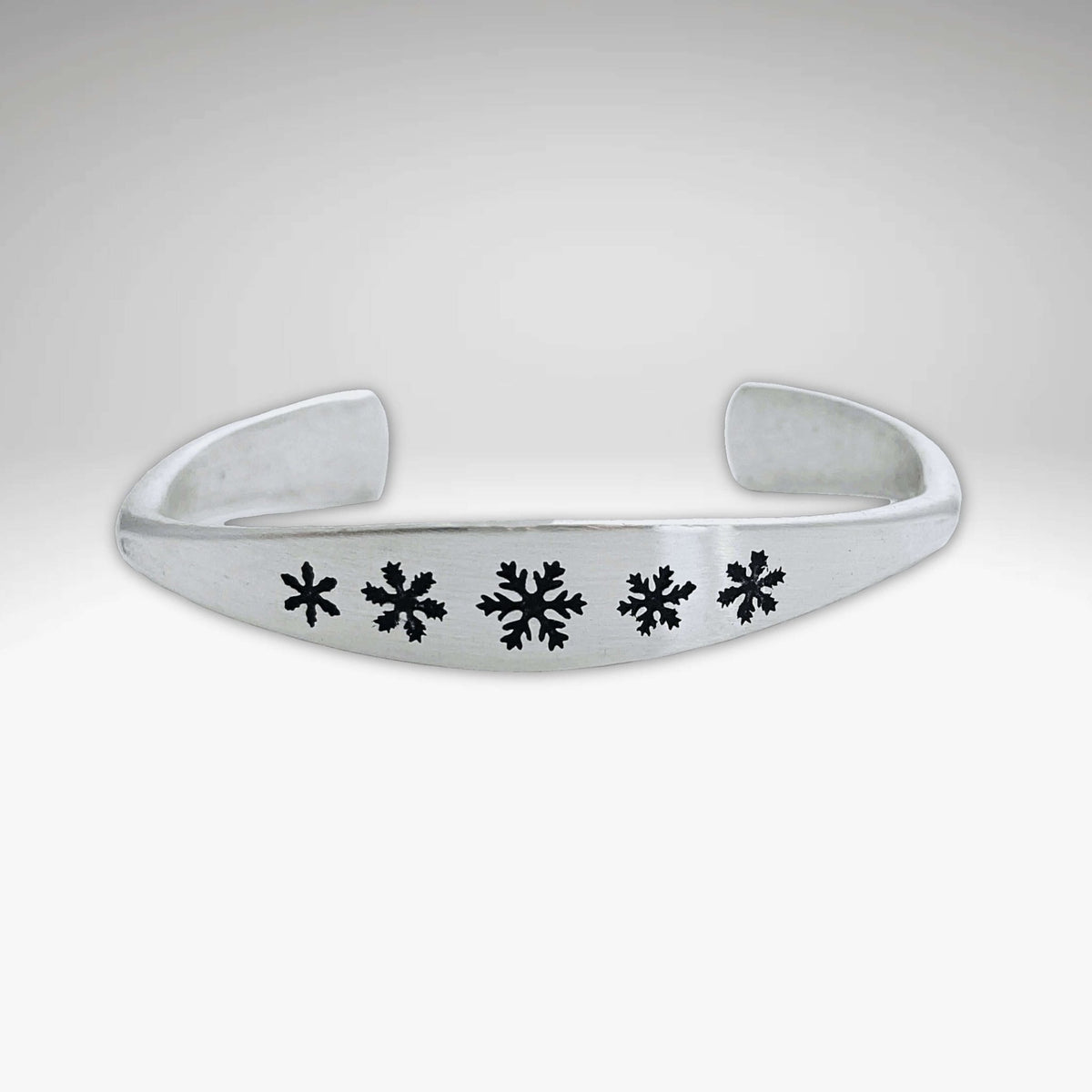 Powder Signet Cuff Bracelet featuring snowflake designs on a handmade adjustable cuff.