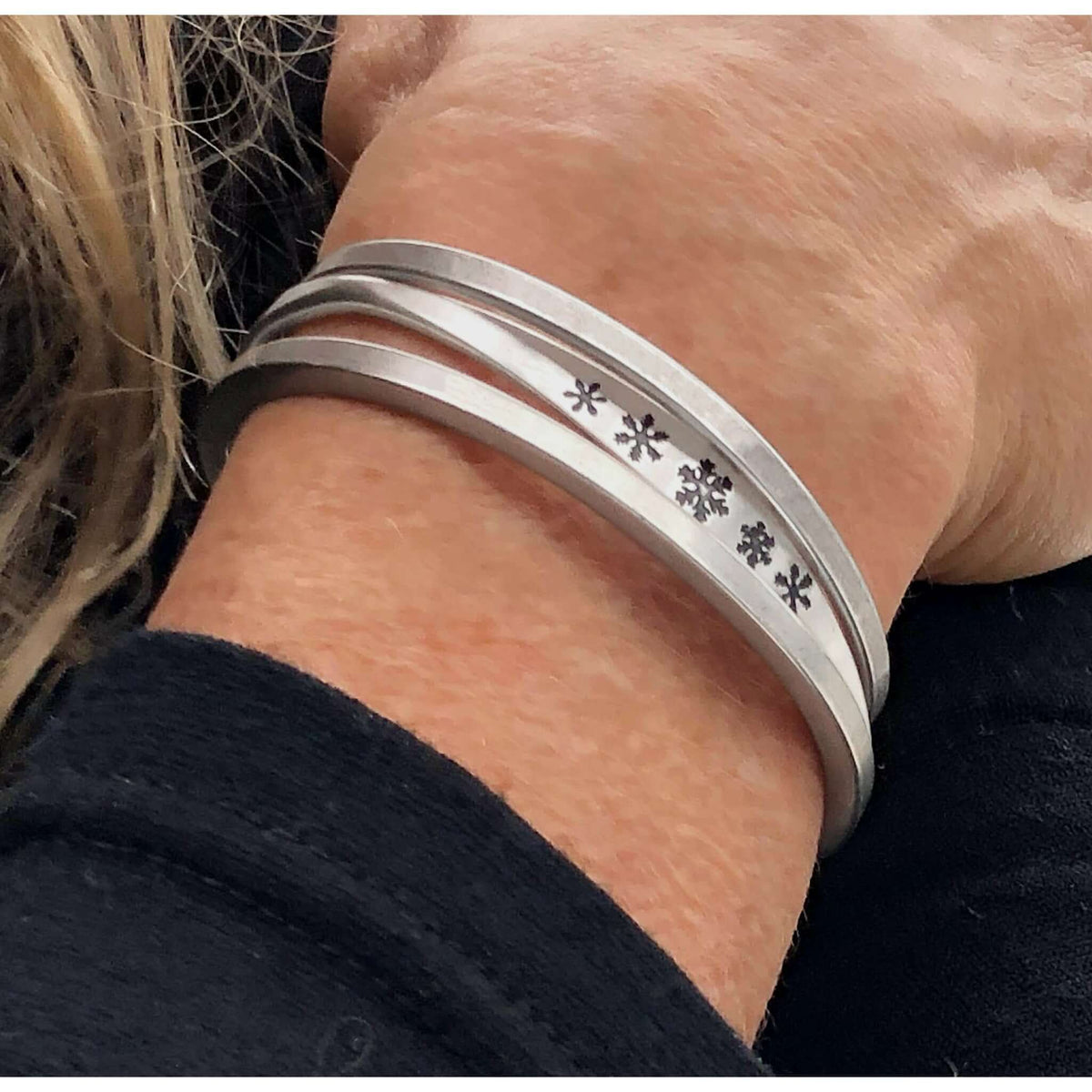 Powder Signet Cuff Bracelet worn on wrist, featuring snowflake designs and adjustable slim profile.