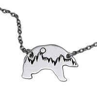 Poya Bear Necklace featuring etched bear silhouette with mountains and sun, crafted in raw brass and adjustable chain.