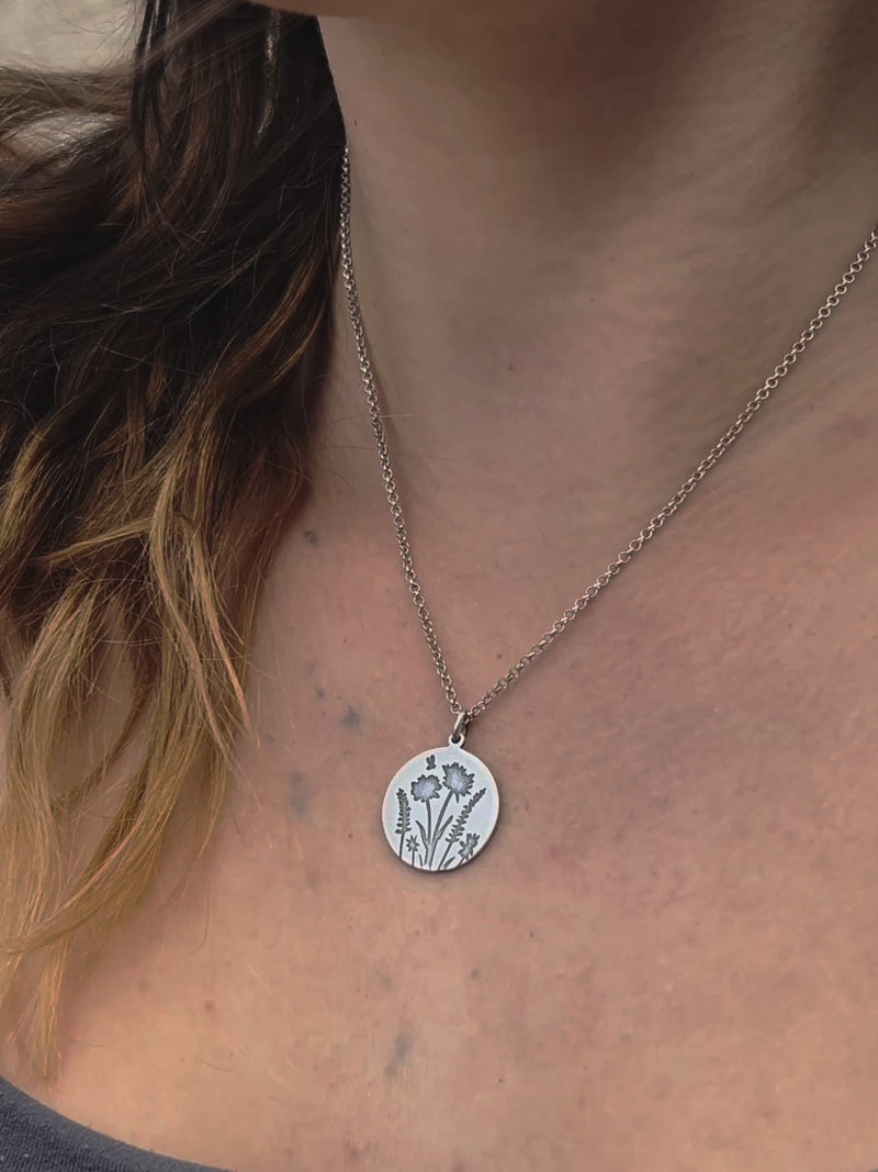 Close-up of the Bee in the Flowers Necklace featuring a circular pendant with wildflowers and a bee.