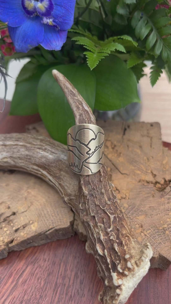 Going to the Sun Road Adjustable Ring displayed on a natural antler with flowers in the background.
