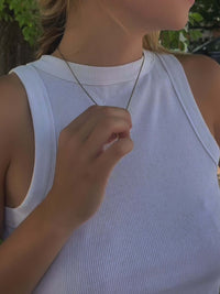 Model wearing a White Horse Necklace on a dainty chain, showcasing its elegant design against a white tank top.