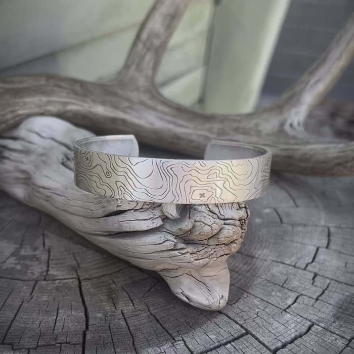 Topo Cuff Bracelet featuring intricate design on a rustic wooden surface.