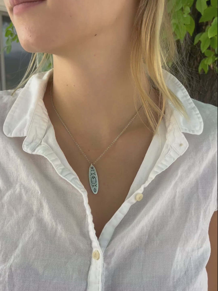 Woman wearing the Upstream Necklace featuring a kayak design, symbolizing river adventures and water experiences.