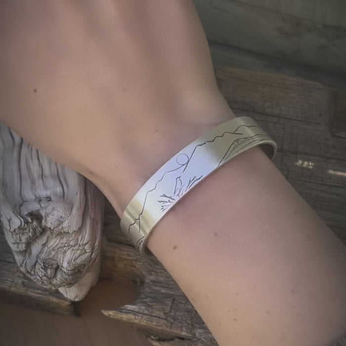 Mtn Bluebird Cuff Bracelet worn on a wrist, showcasing its unique bluebird and mountain design.