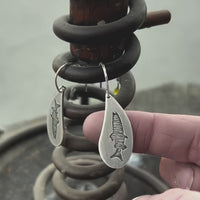 Fishing Around Earrings hanging on a spring, featuring etched fish design on soft teardrop shape.