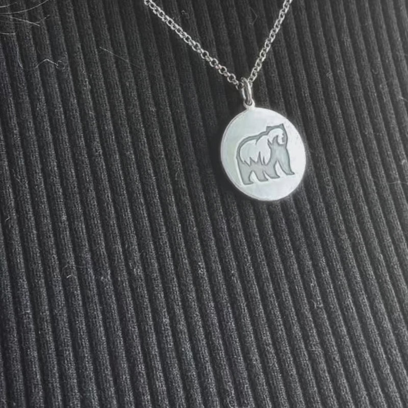 Grizzly Bear Pendant showcased on a necklace, featuring a simple design of a grizzly bear in silver.