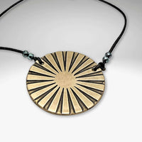 Ray Necklace featuring a sun ray design on a brass disk, complemented by a black cord and decorative beads.