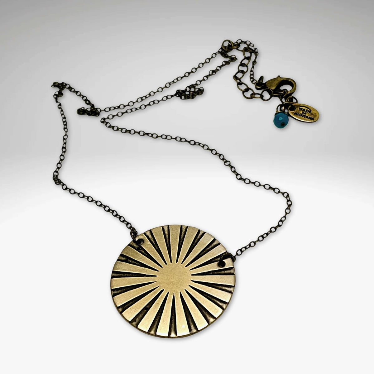 Ray Necklace featuring a sunray disk design in Antique Brass, adjustable chain or monofilament cord options.