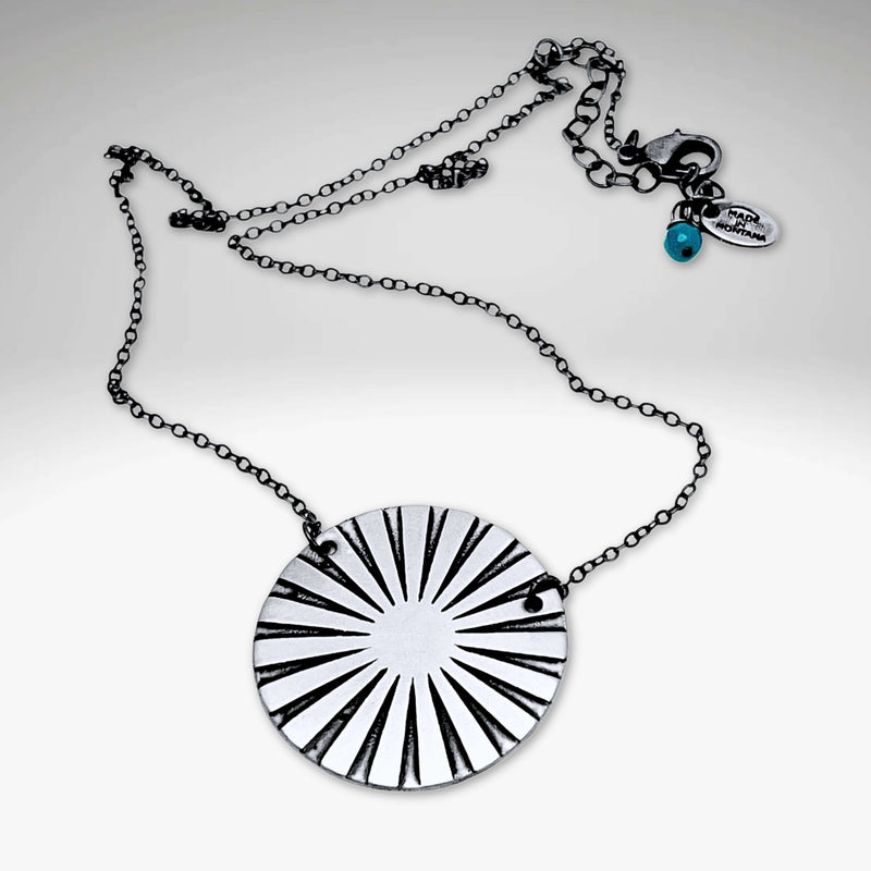 Ray Necklace with sun ray design in silver, showcasing a lightweight chain and unique disk pattern.