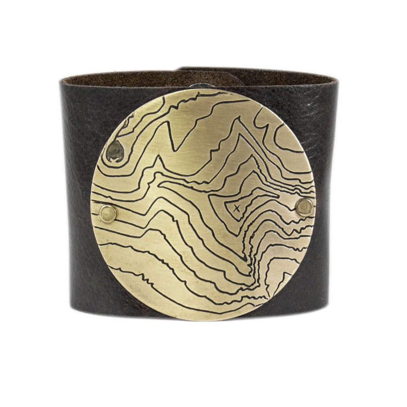 Rising Wolf Disk Leather Cuff featuring a topographical design in antique brass on a genuine leather band.