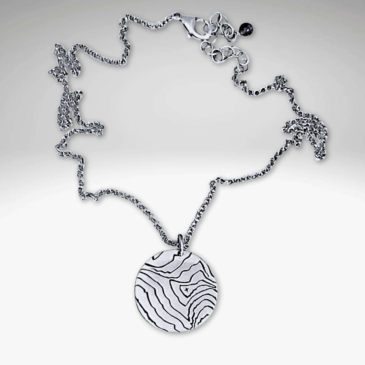 Rising Wolf Necklace featuring a detailed topographic map design in matte silver finish.