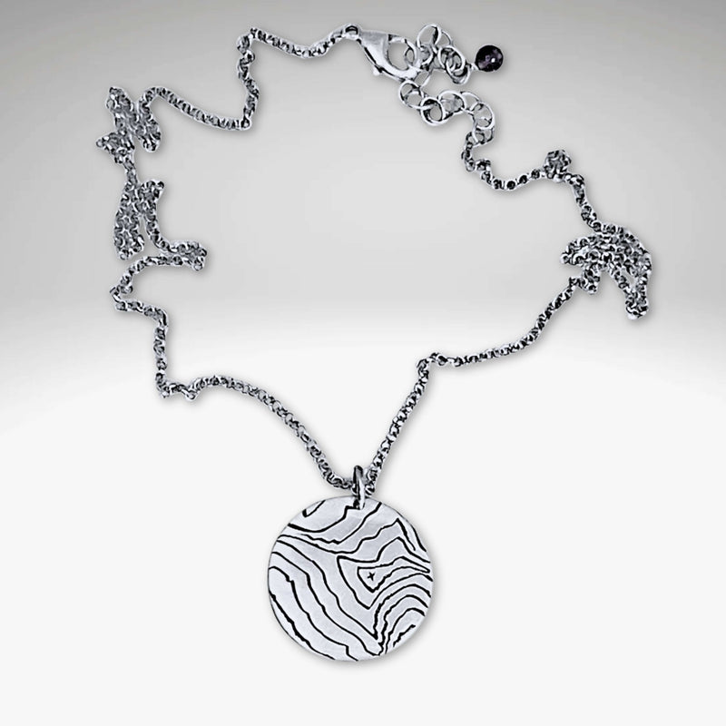 Rising Wolf Necklace featuring a detailed topographic map design in matte silver finish.