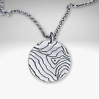Rising Wolf Necklace featuring a detailed topographic map design on a circular pendant in Matte Silver finish.