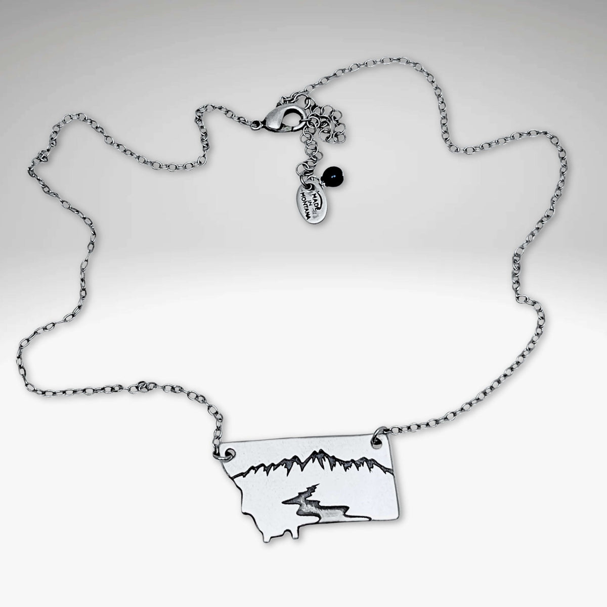 River Run Necklace depicting Montana's mountains and river, perfect for outdoor enthusiasts and nature lovers.