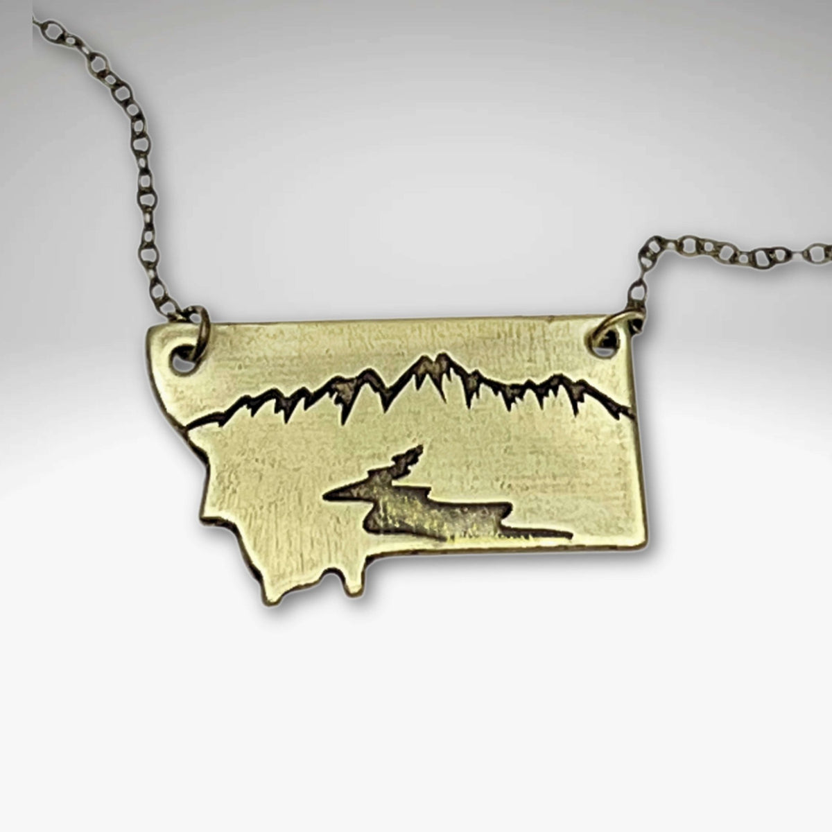 River Run Necklace showcasing intricate Montana design with mountains and river, symbolizing adventure and nature's beauty.