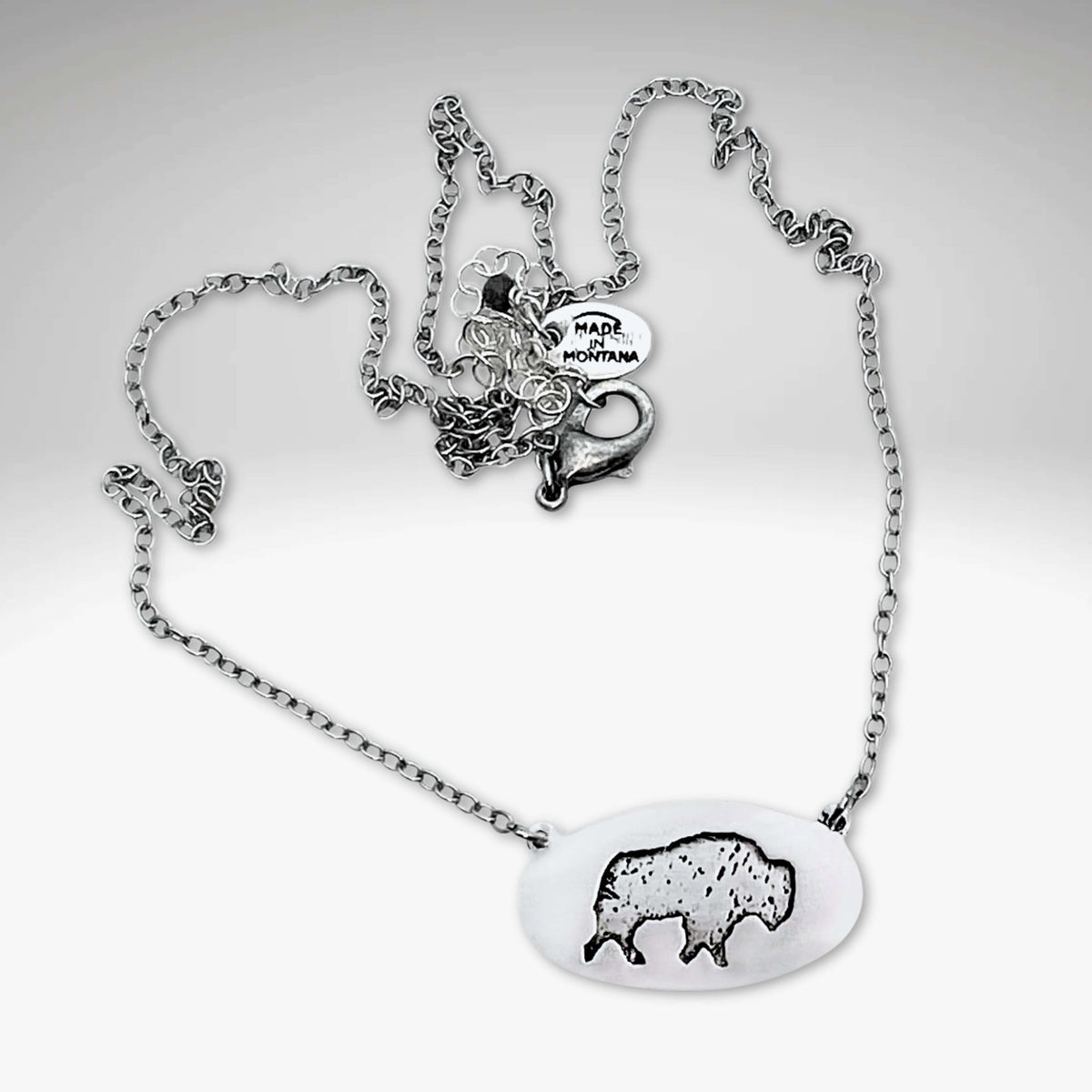 Roam Free Necklace featuring a buffalo design on an oval pendant with a silver chain.
