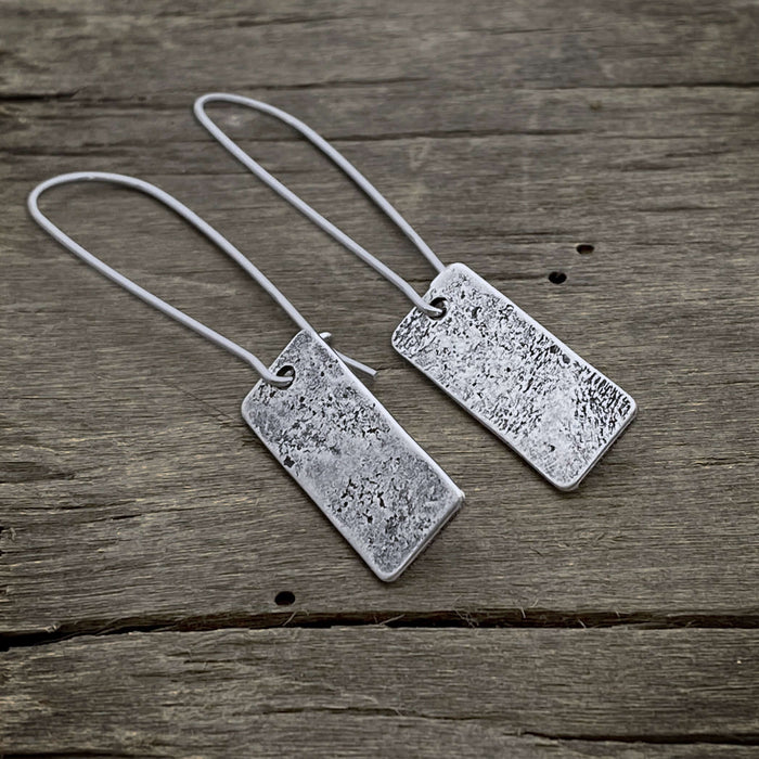 Rubble Rectangles Earrings made of hand-hammered brass with a matte silver finish, featuring kidney style earwires.