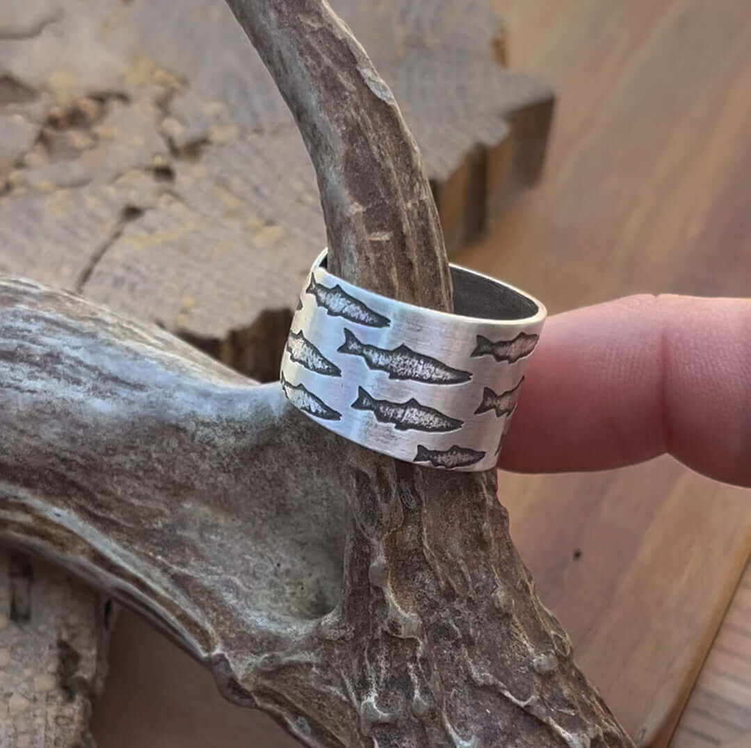 Salmon Run Adjustable Ring featuring salmon etchings, handmade in raw brass, resting on natural wood.