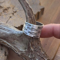 Salmon Run Adjustable Ring featuring salmon etchings, handmade in raw brass, resting on natural wood.