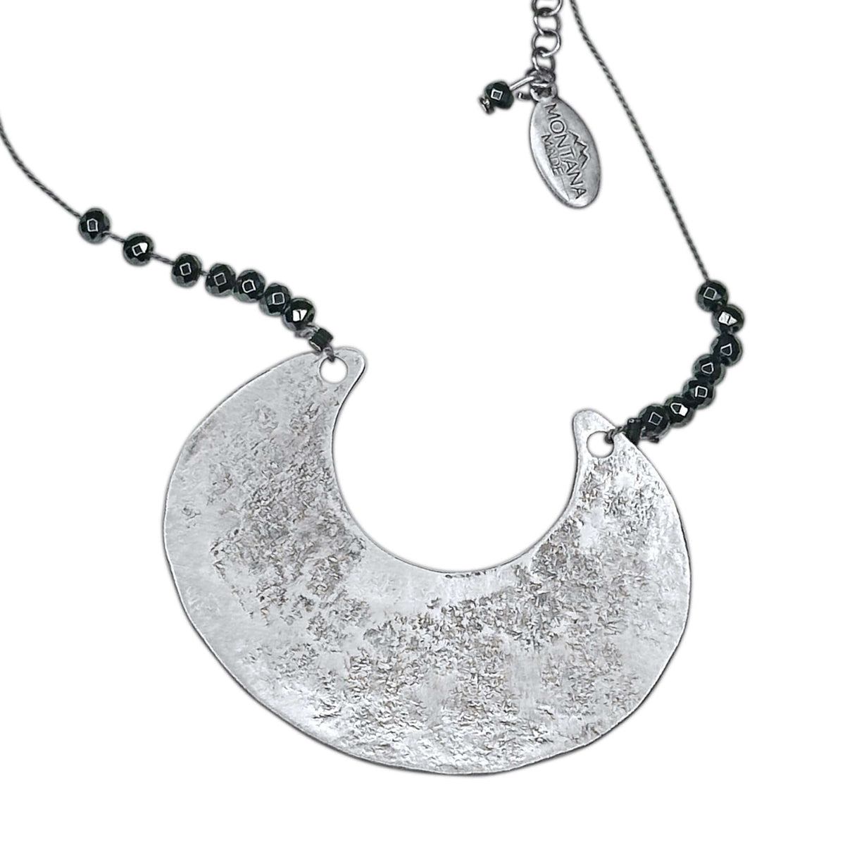 Scoop Necklace featuring a large geometric silver pendant on a silk cord with hematite beads, adjustable length.