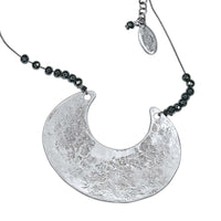 Scoop Necklace featuring a large geometric silver pendant on a silk cord with hematite beads, adjustable length.