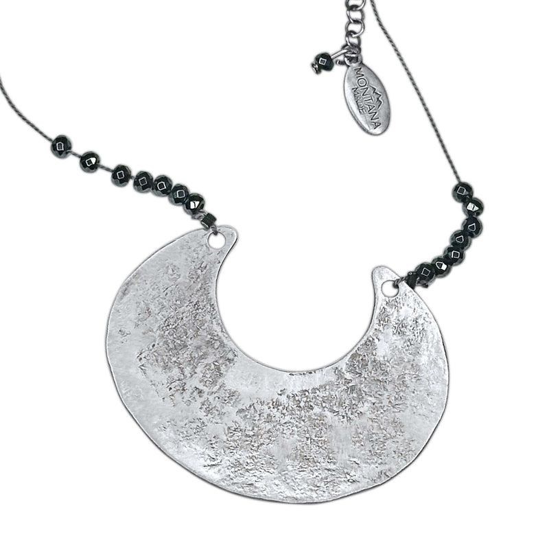 Scoop Necklace featuring a large geometric silver pendant on a silk cord with hematite beads, adjustable length.