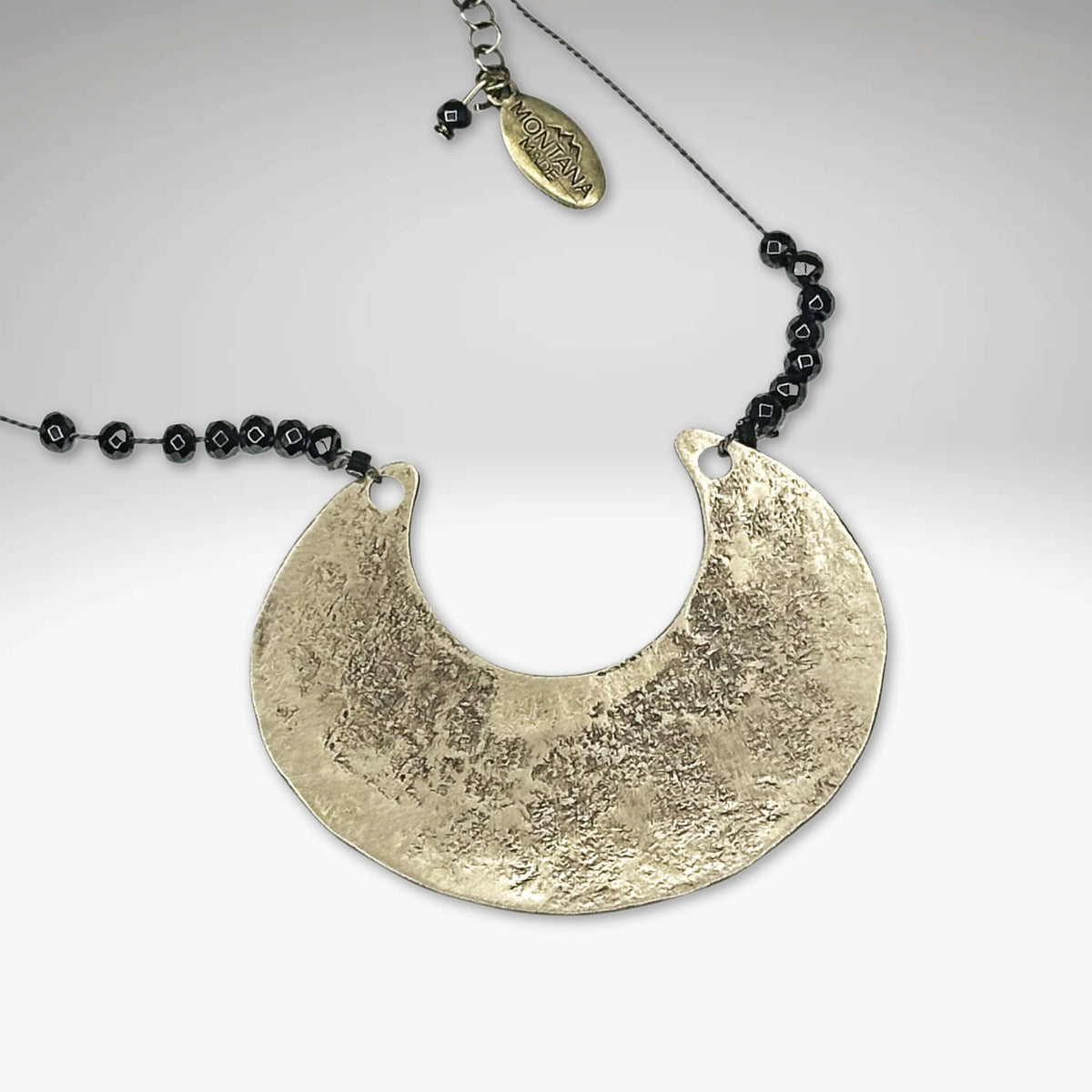 Scoop Necklace featuring a large metallic scoop pendant on a delicate silk cord with hematite beads.