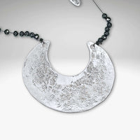 Scoop Necklace featuring a large geometric pendant on a delicate silk cord with hematite beads, adjustable from 16" to 18".