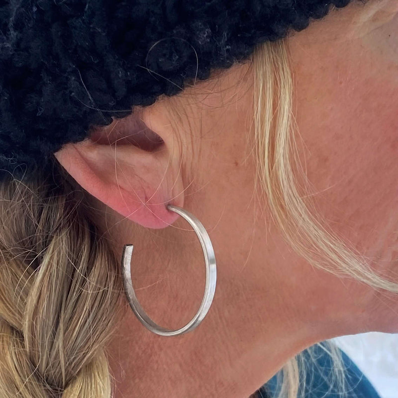 Simple Hoop Earrings displayed on a model's ear, showcasing the smooth silver finish and stylish design.