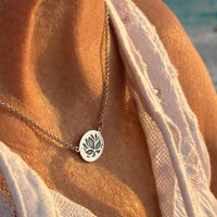 Model wearing the Simple Lotus Necklace featuring a lotus etching on a small oval pendant in matte silver.