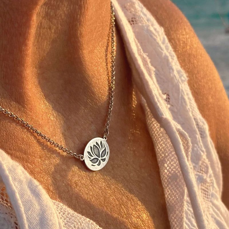 Model wearing the Simple Lotus Necklace featuring a lotus etching on a small oval pendant in matte silver.