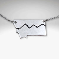 Simple Montana Necklace featuring a silver pendant shaped like Montana with mountain design, on a light cable chain.