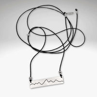 Simple Teton Mountain Necklace featuring a brass pendant on a black adjustable cord.