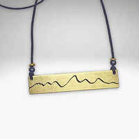 Simple Teton Mountain Necklace with etched brass pendant and blue beaded chain.