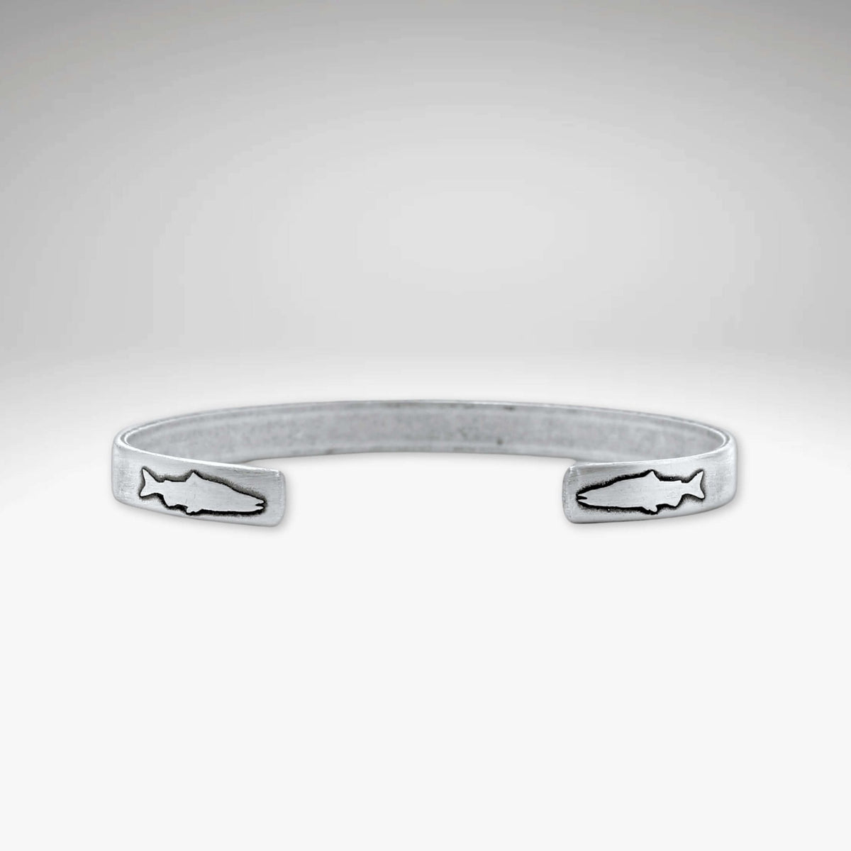 Skinny Fish Cuff Bracelet with etched fish design on tips, showcasing raw brass texture and stylish appeal.