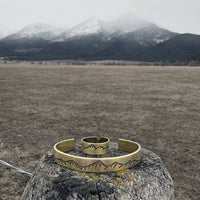 Snowcap Mountains Cuff Bracelet- Great gift for men and women displayed on a wooden post with a mountainous background.