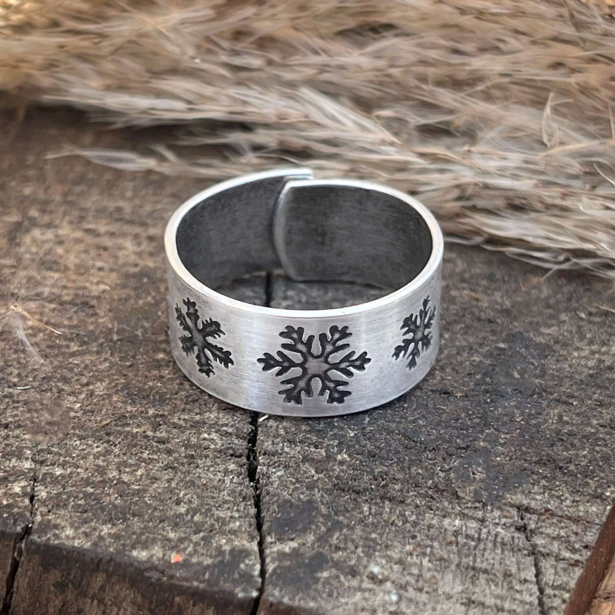 Close-up of the Snowfall Adjustable Ring featuring etched snowflakes on a matte silver finish, adjustable for sizes 7 to 11.