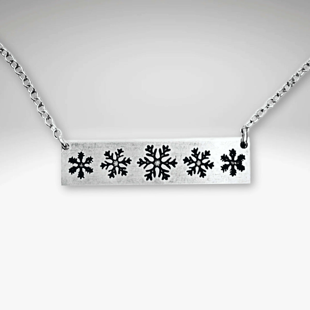 Close-up of the Snowfall Necklace featuring a snowflake bar design in Matte Silver finish.