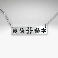 Close-up of the Snowfall Necklace featuring a snowflake bar design in Matte Silver finish.