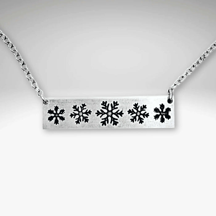 Close-up of the Snowfall Necklace featuring a snowflake bar design in Matte Silver finish.