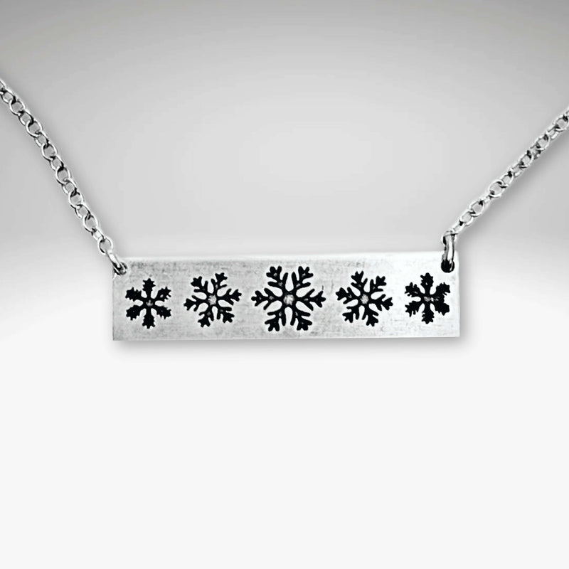 Close-up of the Snowfall Necklace featuring a snowflake bar design in Matte Silver finish.