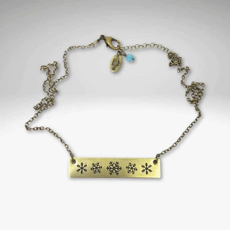 Snowfall Necklace featuring a snowflake bar design on an Antique Brass finish with an adjustable chain.