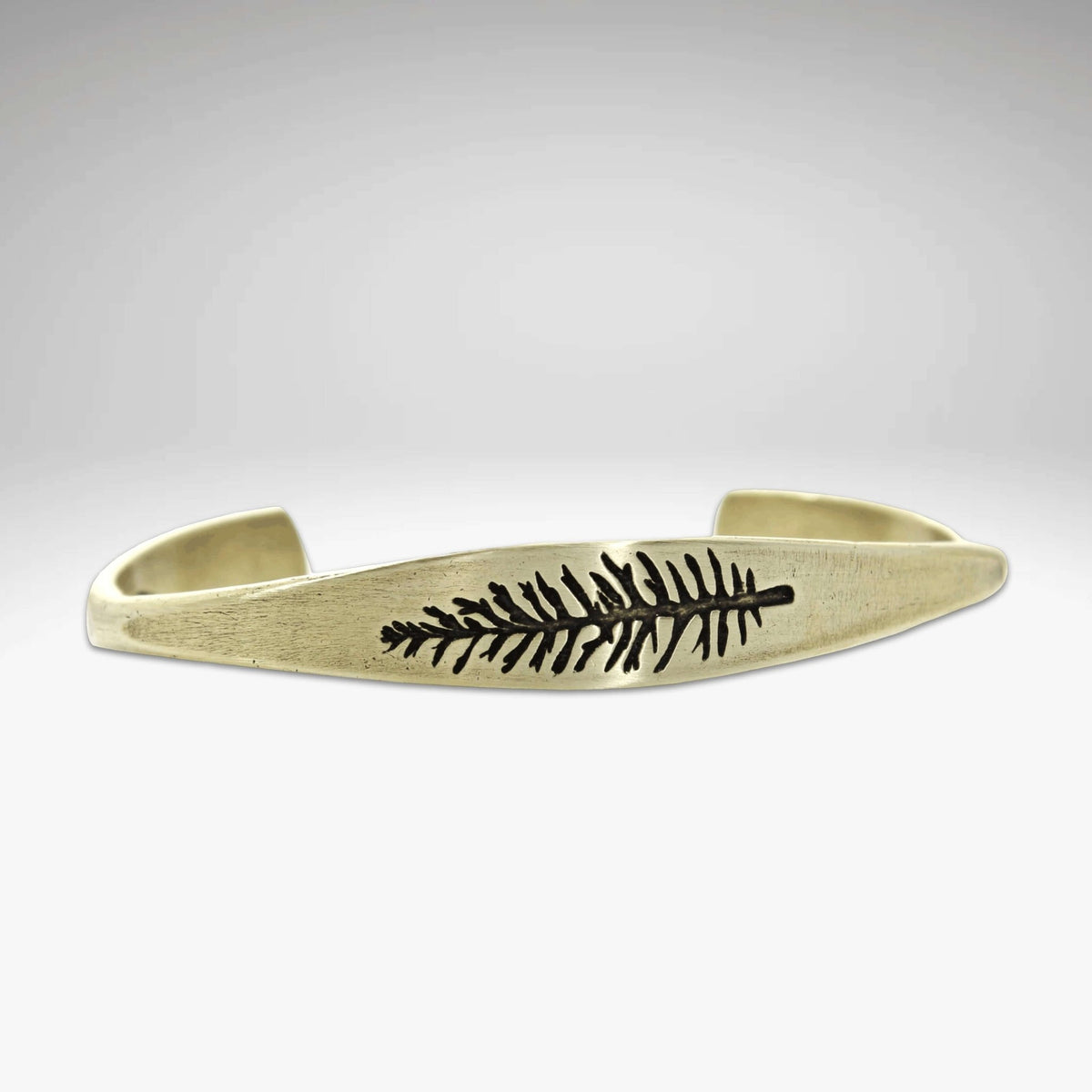 Spruce Signet Cuff Bracelet showcasing a detailed spruce outline etching on a tapered gold cuff.