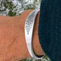 Spruce Signet Cuff Bracelet worn on wrist, showcasing detailed spruce outline etching.