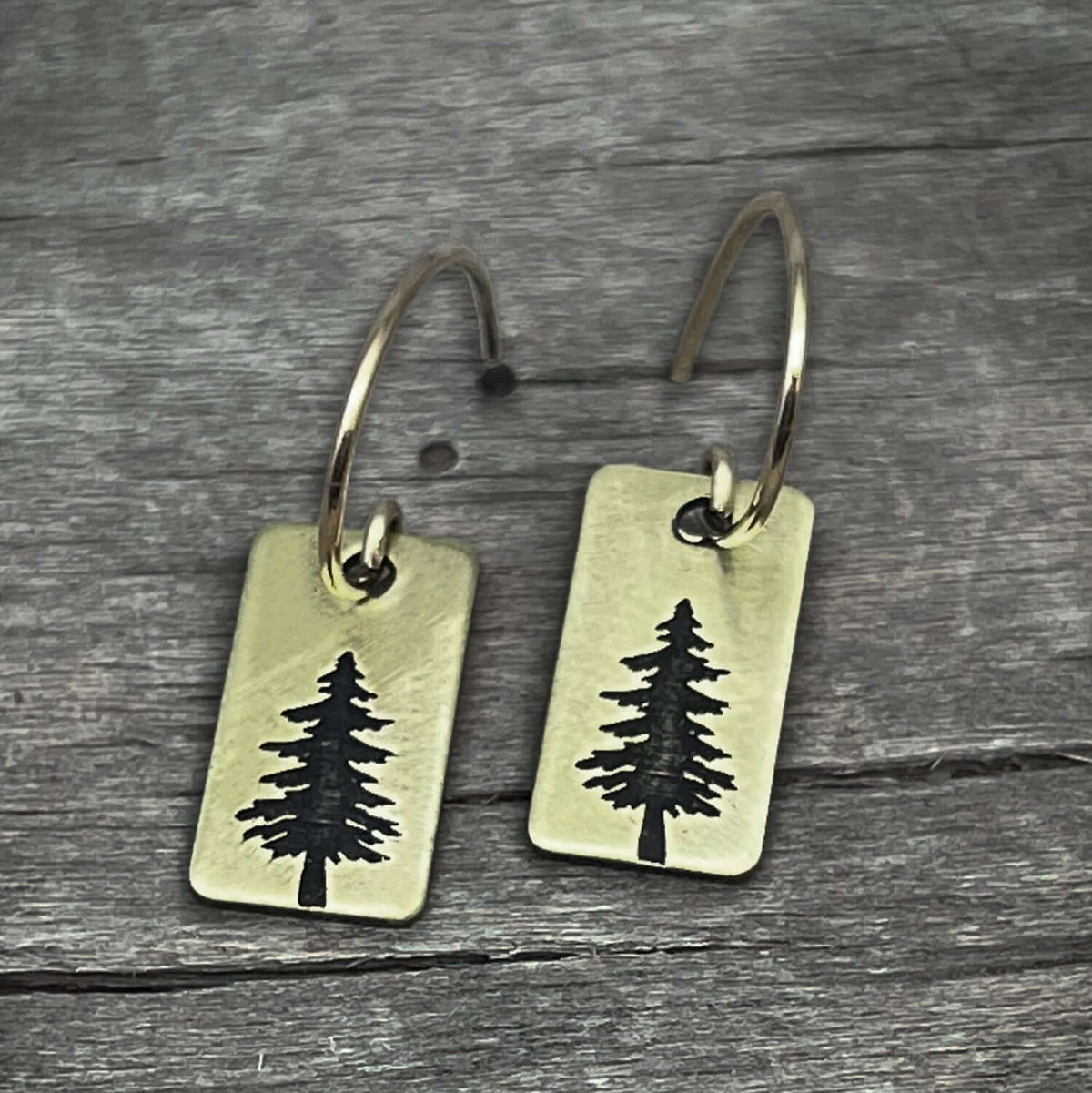 Spruce Tree Hoop Earrings made of antique brass with a small spruce tree design on a rounded rectangle.