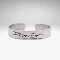 St. Mary Cuff Bracelet featuring intricate mountain and sun designs on a silver adjustable cuff.