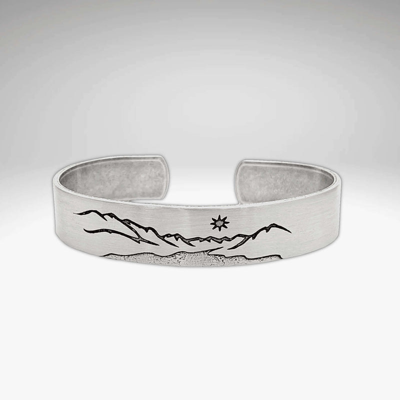 St. Mary Cuff Bracelet featuring intricate mountain and sun designs on a silver adjustable cuff.