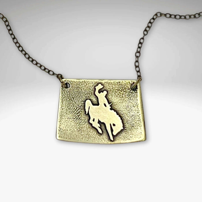 Steamboat Necklace featuring a raw brass cowboy silhouette on a textured pendant.