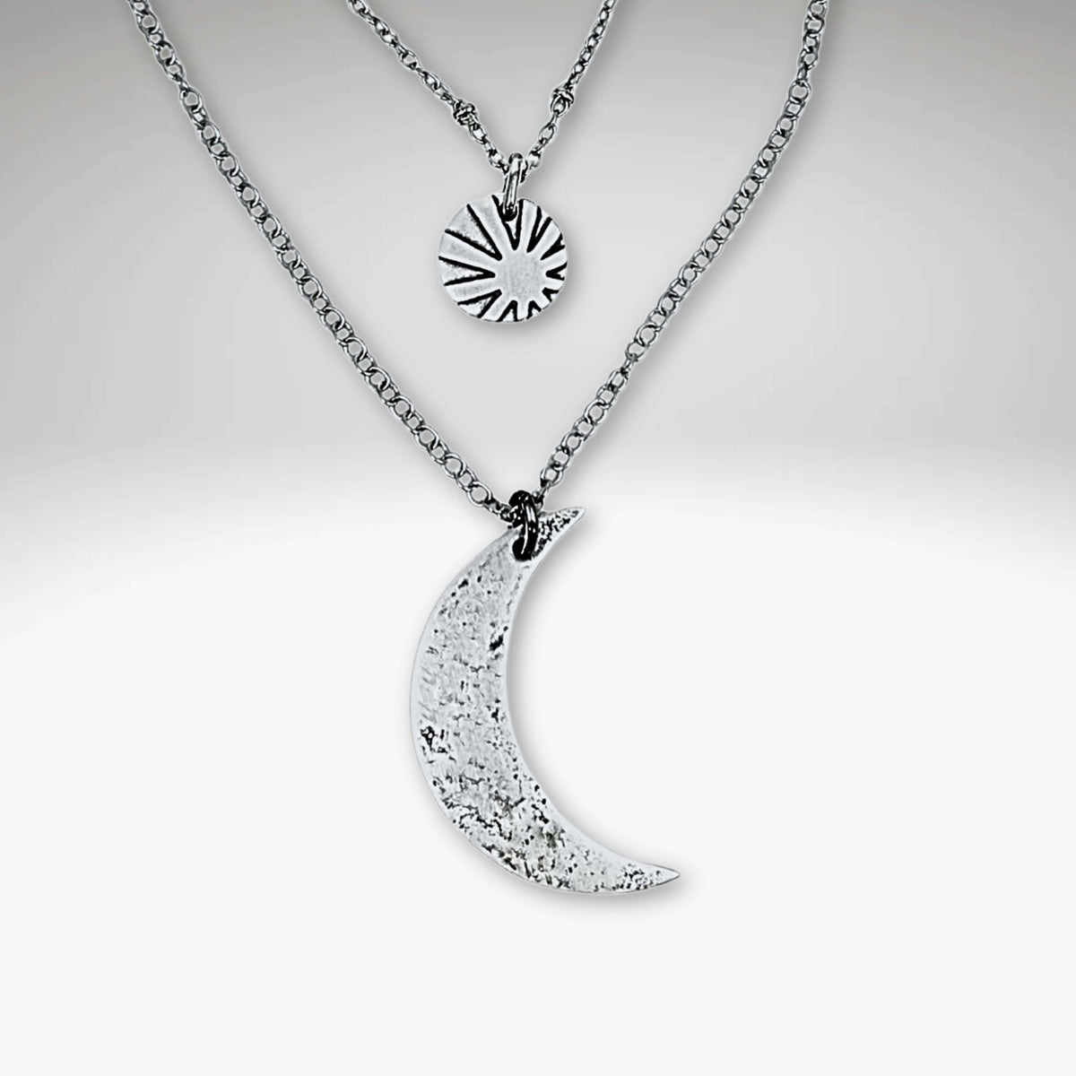 Sun and Moon Long Layered Necklace featuring a hammered crescent moon and sun charm in matte silver.